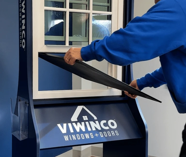 Man in blue viwinco shirt removing screen from a double hung viwinco window case