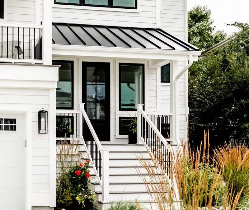exterior of white home with black door and black windows. stairs lead up to the door