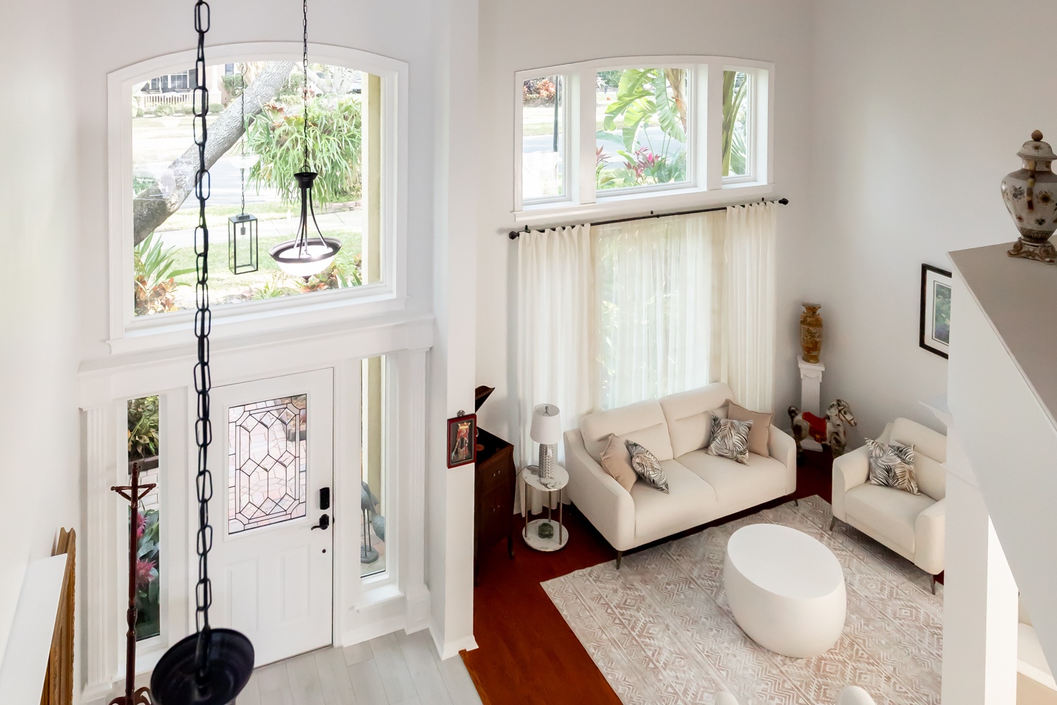 interior of a white home with a large picture window above a door, as well as three picture windows above a couch.