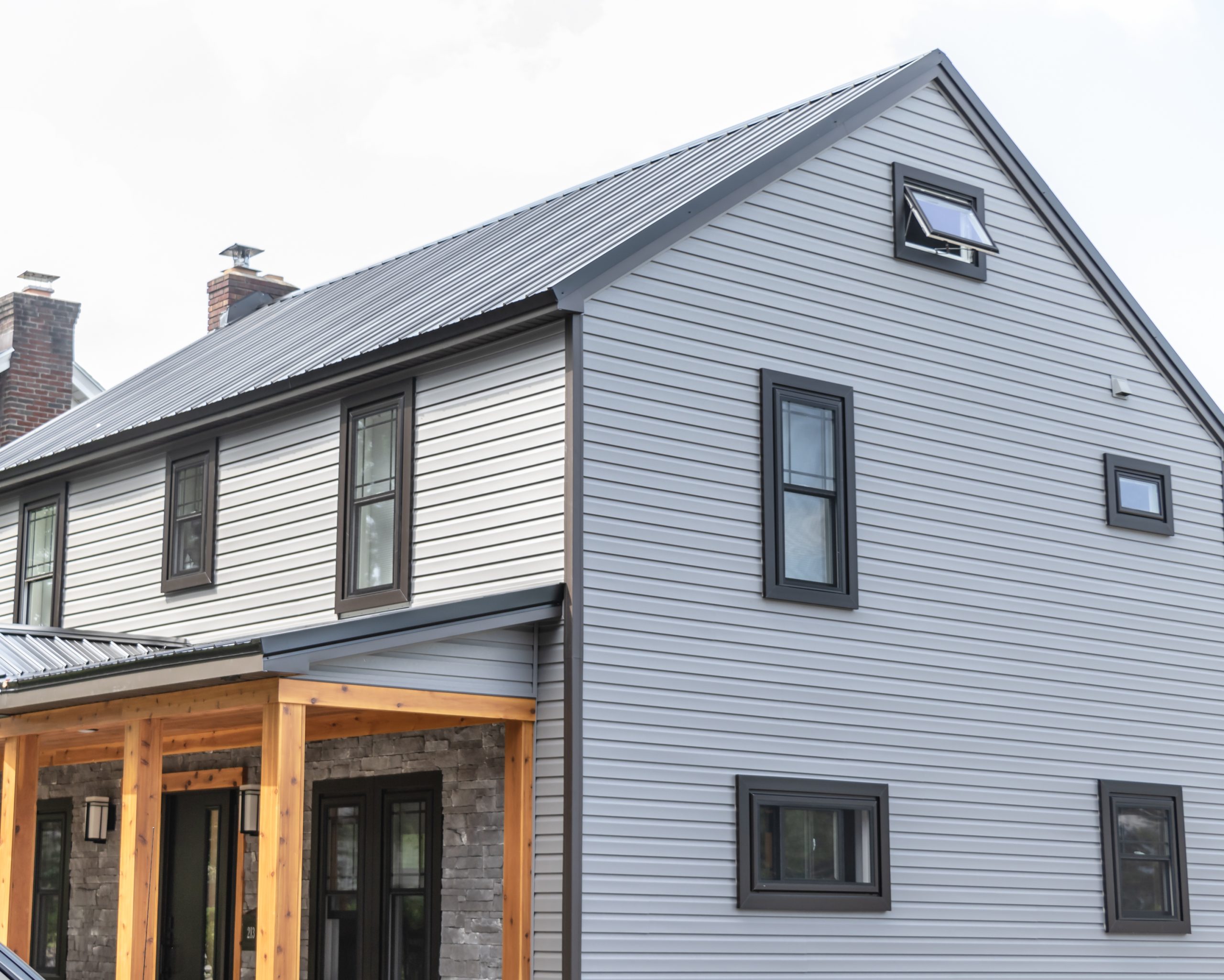 grey home with midnight black windows, including a sliding, hung, awning, and picture window